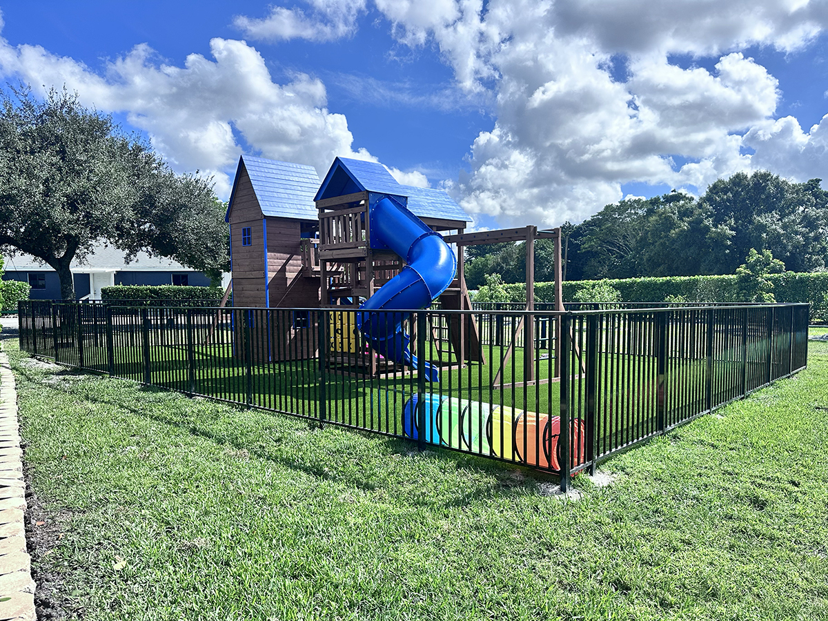 Black aluminum fence installed around a backyard playground in Davie, Broward County, Florida, by Atanda Fence of South Florida.
