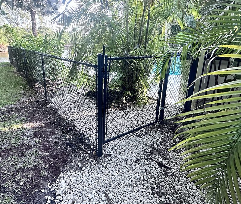 Black vinyl-coated chain link fence with a matching gate installed by Atanda Fence of South Florida in Parkland, Broward County, FL.