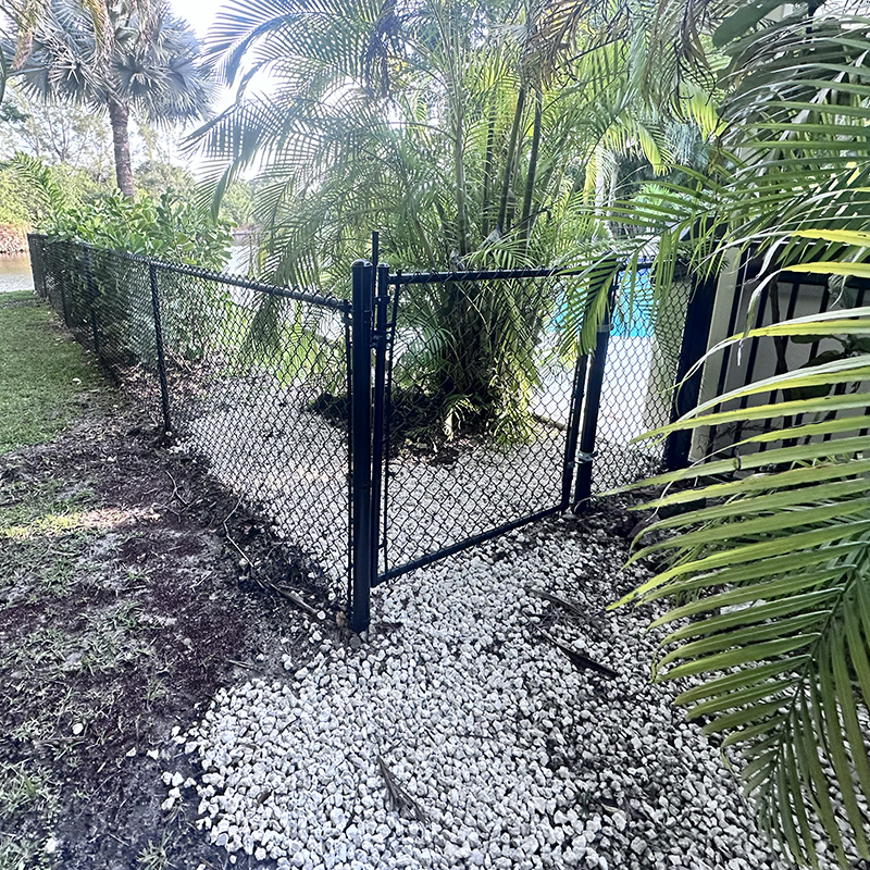 Black vinyl-coated chain link fence with a matching gate installed by Atanda Fence of South Florida in Parkland, Broward County, FL.