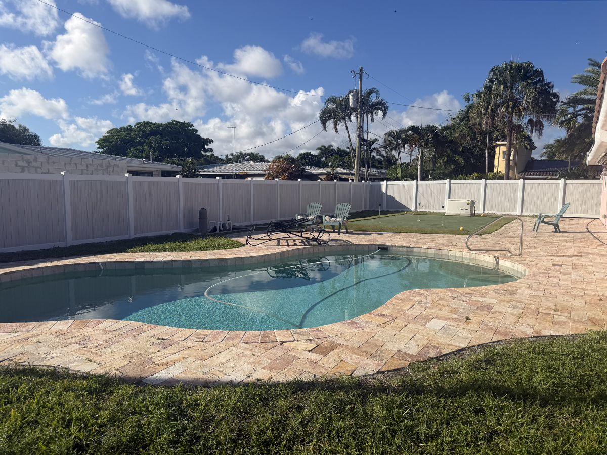 Two-tone Aspen PVC privacy fence surrounding a backyard swimming pool at a home in Oakland Park, FL.