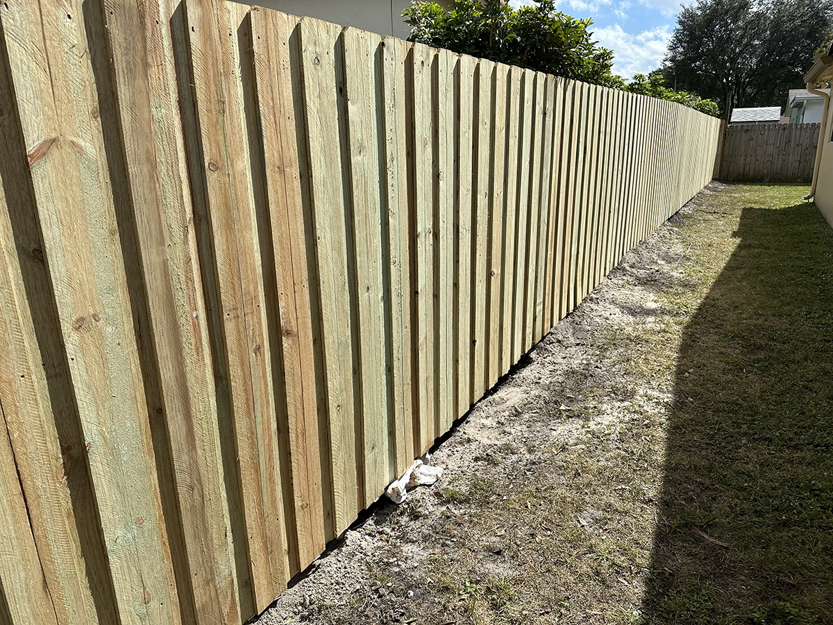 Side view of a newly installed board-on-board wood fence providing backyard privacy at a residential property in Plantation, Broward County, FL.